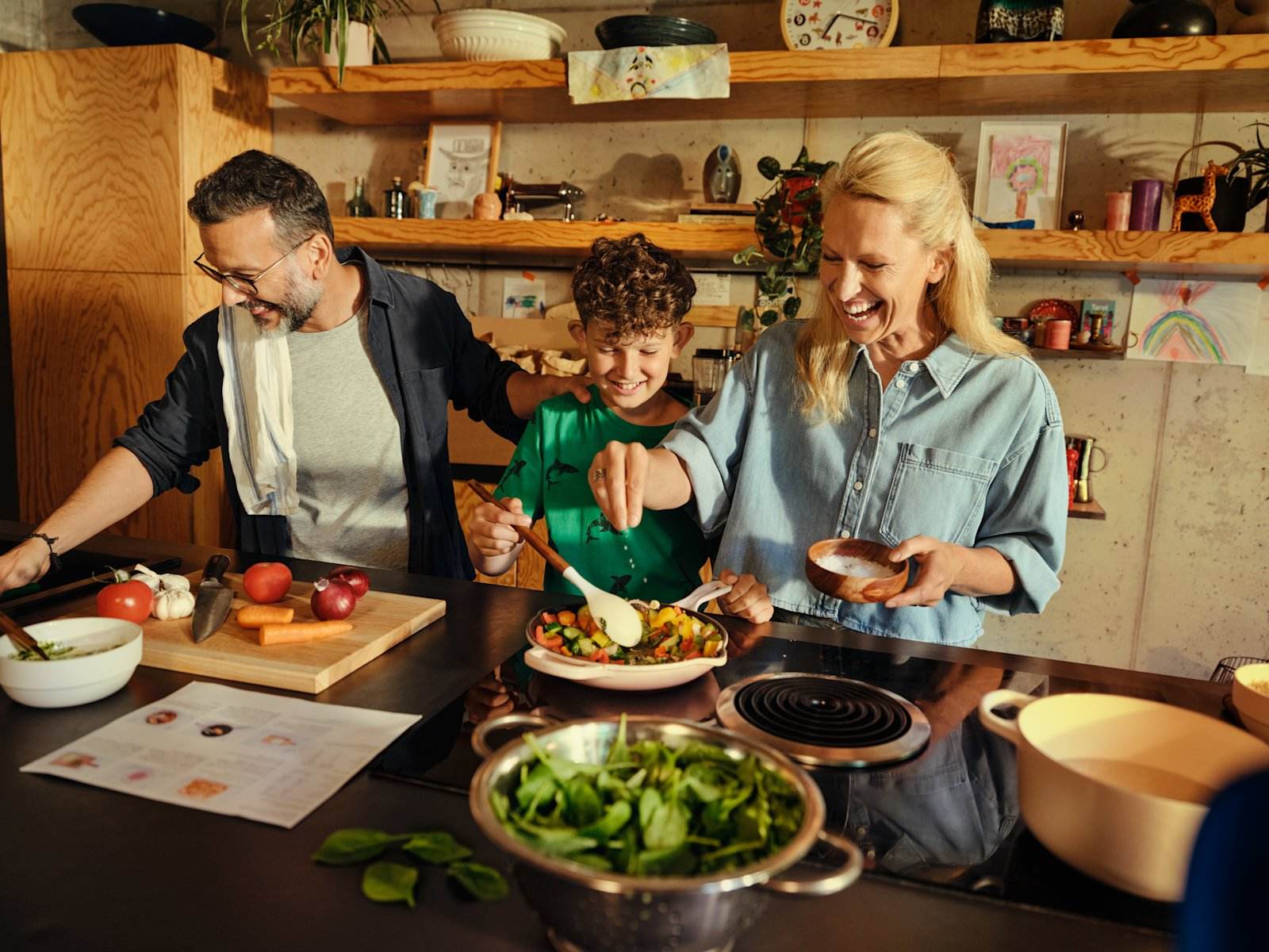 Familie lager middag sammen på kjøkkenet med råvarer fra HelloFresh Familie lager middag sammen på kjøkkenet med råvarer fra HelloFresh